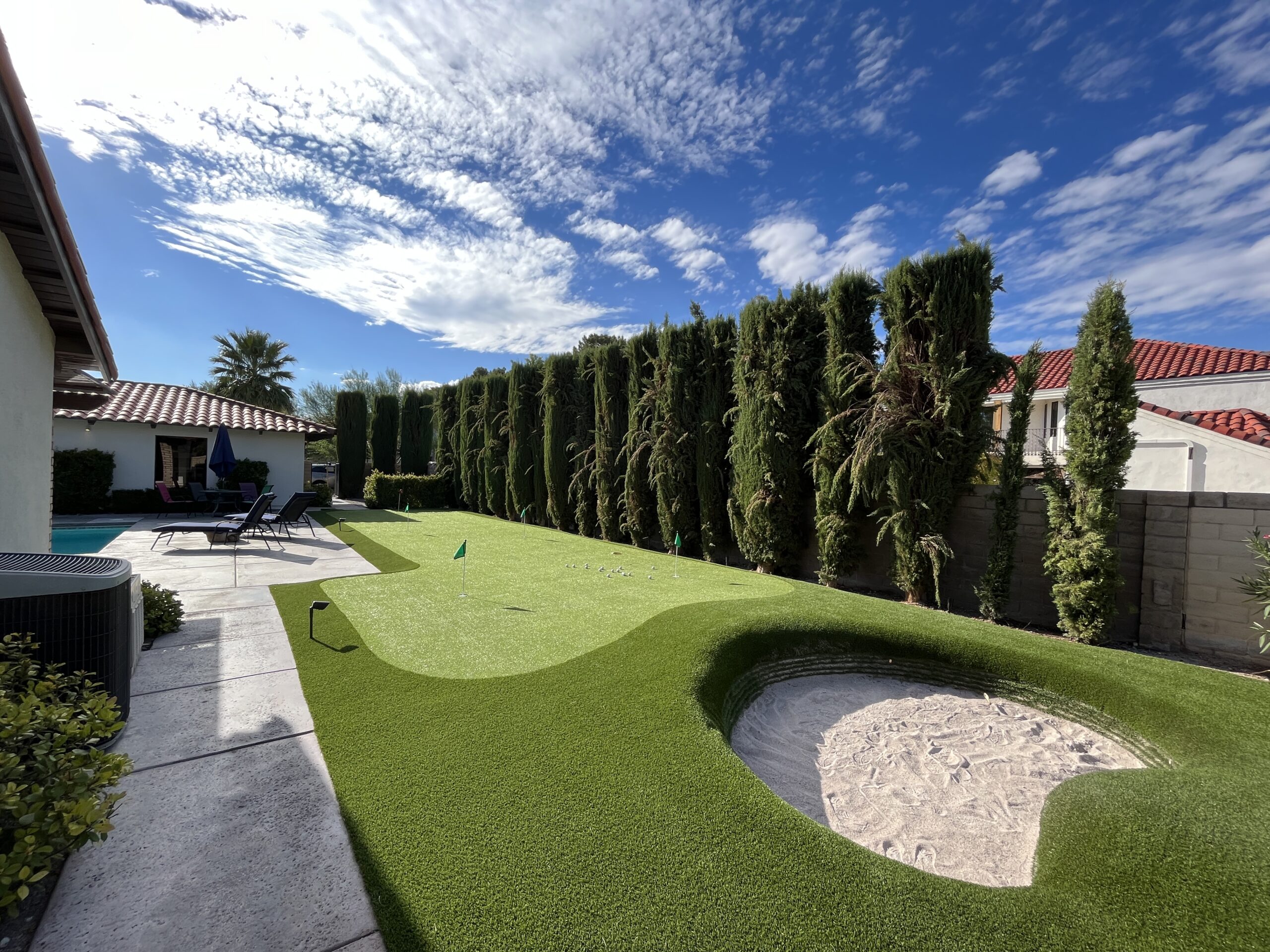 A backyard with a putting green and a small hole. A backyard with a putting green and a small hole.