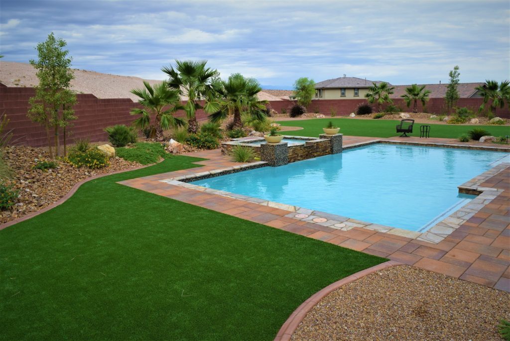 A pool with grass and palm trees in the background. A pool with grass and palm trees in the background.